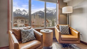 A modern living room with leather sofas and a large window offering a mountain view. - 3 Sisters Mountain Views | Hot Tub & Heated Pool (Canmore)
