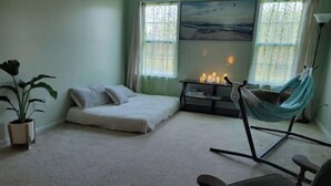 A bedroom with a bed, a hammock, a chair, a plant, and a painting on the wall. - Harvest of tranquillity (Dover)