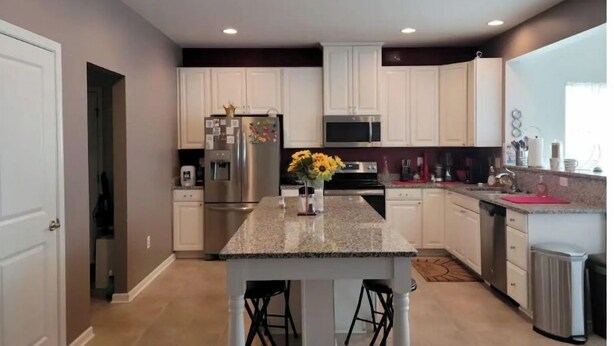 A modern kitchen with white cabinets, stainless steel appliances, and a granite countertop. - Harvest of tranquillity (Dover)