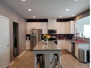 A modern kitchen with white cabinets, stainless steel appliances, and a granite countertop. - Harvest of tranquillity (Dover)