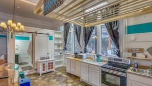 Une cuisine moderne avec des meubles blancs, un four encastré et une fenêtre avec des rideaux.