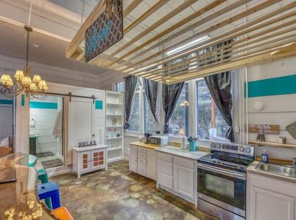 A modern kitchen with white cabinets, a built-in oven, and a window with curtains.