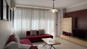 Un salon moderne avec un canapé, une table basse, un téléviseur et un meuble en bois.