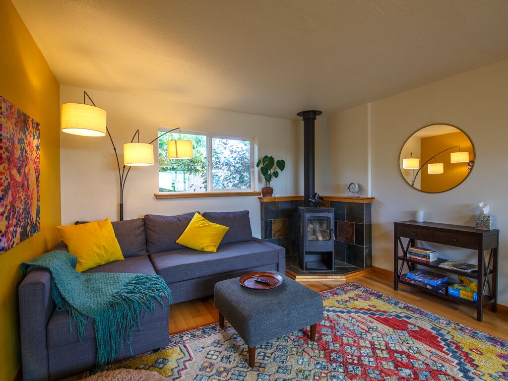 Una sala de estar acogedora con sofá, una mesita, chimenea y un espejo en la pared.