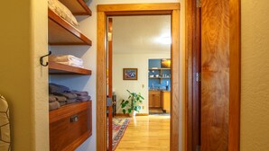 Un pasillo con estantes de madera, una planta en maceta y vista a una cocina.
