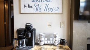 Une machine à café, des tasses et une pancarte sur laquelle est écrit : « Bienvenue au chalet de ski ».