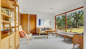 A cozy living room with a bookshelf, a sofa, a coffee table, and a view of the outdoors. - Amazing home in Rødby with WiFi (Rødby)