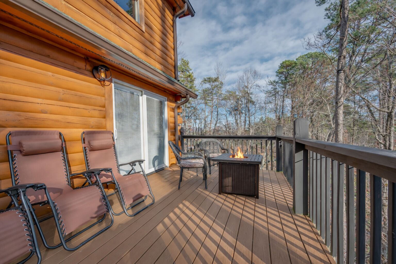 A wooden deck with two lounge chairs and a fire pit.