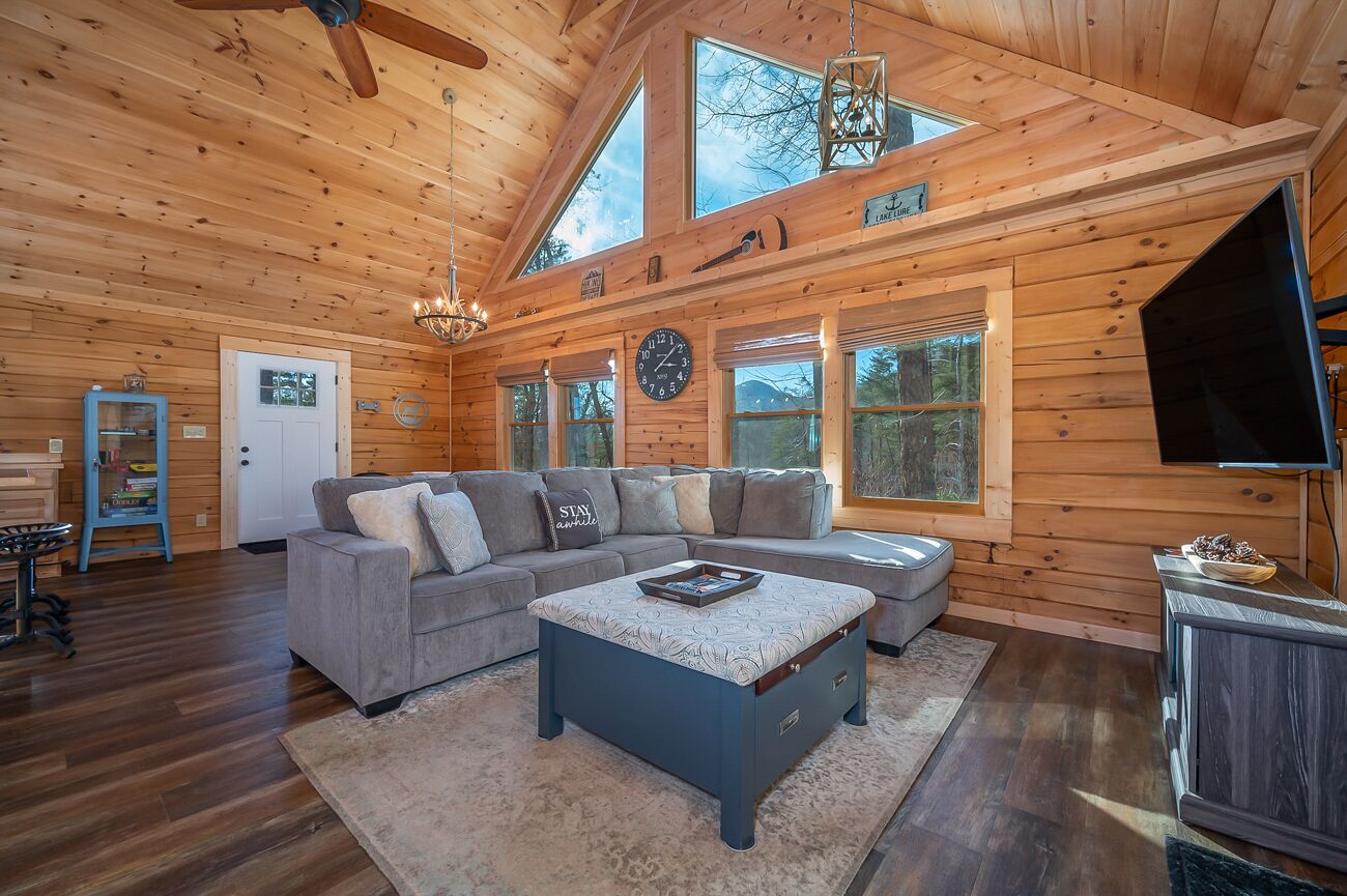 A log cabin interior with a large sofa, a coffee table, and a television.