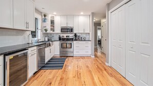 Una cocina moderna con armarios blancos, electrodomésticos de acero inoxidable y piso de madera.