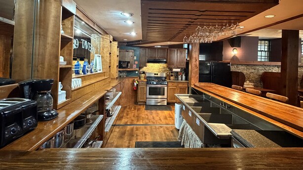 Un restaurante con mostradores de bar de madera, una zona de cocina y un comedor con mesas y sillas.