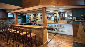 Una zona de bar con taburetes, una barra y diversos utensilios.