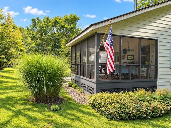 A house with a porch, a flag, and a garden. - Comfortable Country Charm with Otsego Lake Access (Cooperstown)