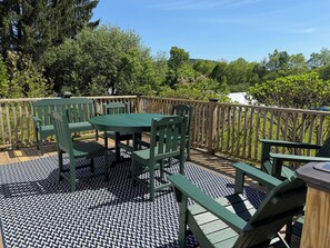 Eine Terrasse mit einem grünen Tisch und Stühlen, umgeben von einem hölzernen Geländer.