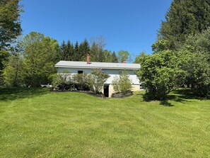 A single-story house with a front porch, surrounded by a well-maintained lawn and trees.