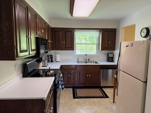 A kitchen with wooden cabinets, a microwave, a stove, a refrigerator, and a window with a view of greenery. - Changing Seasons - Game room, immaculate ranch (Hartwick)