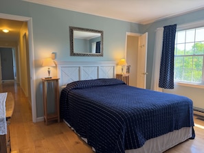 A bedroom with a large bed, two bedside tables with lamps, a mirror above the bed, and a window with curtains. - Changing Seasons - Game room, immaculate ranch (Hartwick)