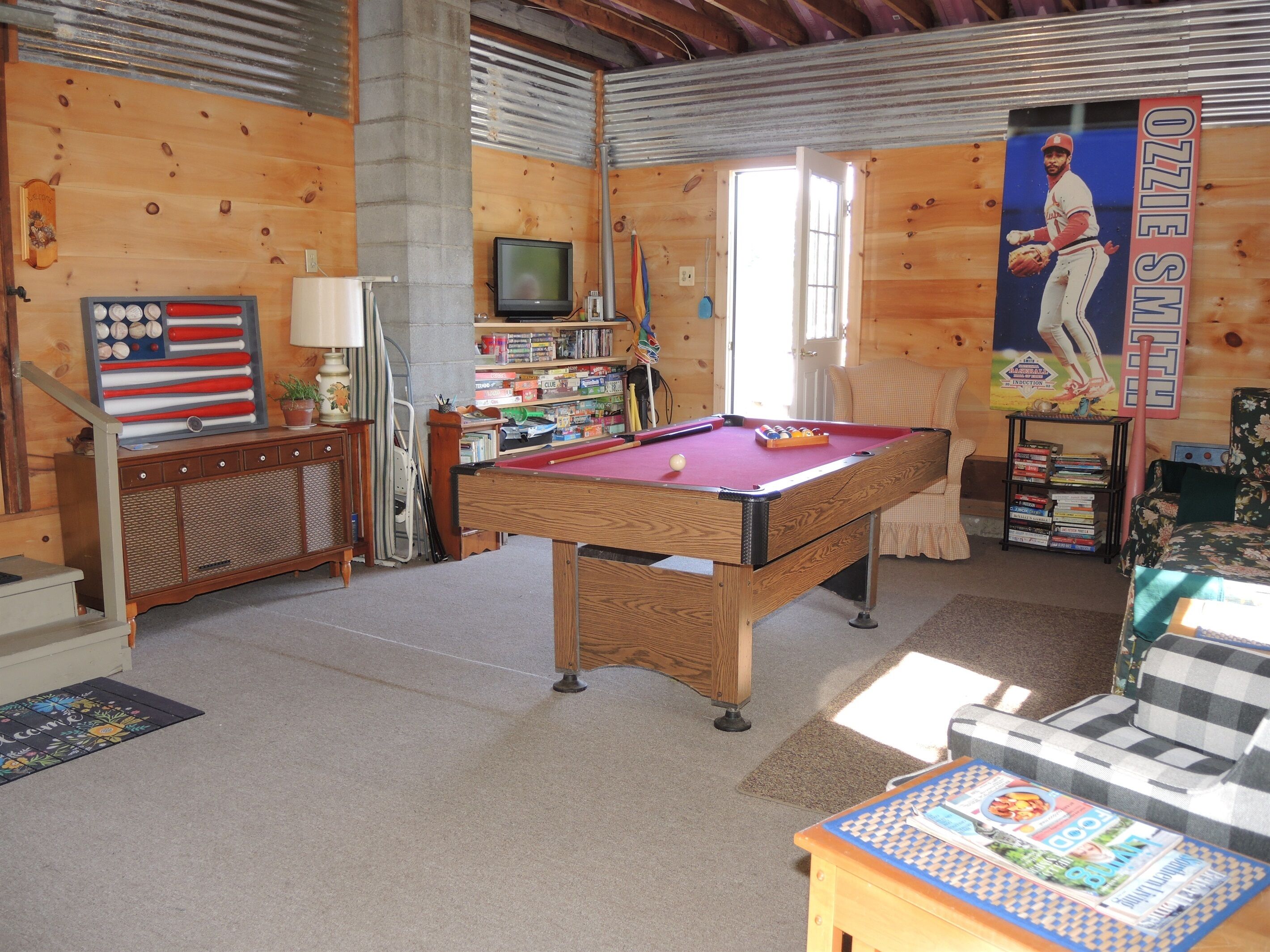 A room with a pool table, a television, and a bookshelf.