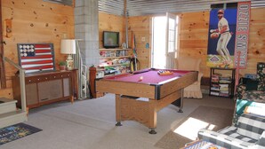 Ein gemütliches Zimmer mit Billardtisch, Fernseher und Bücherregal.