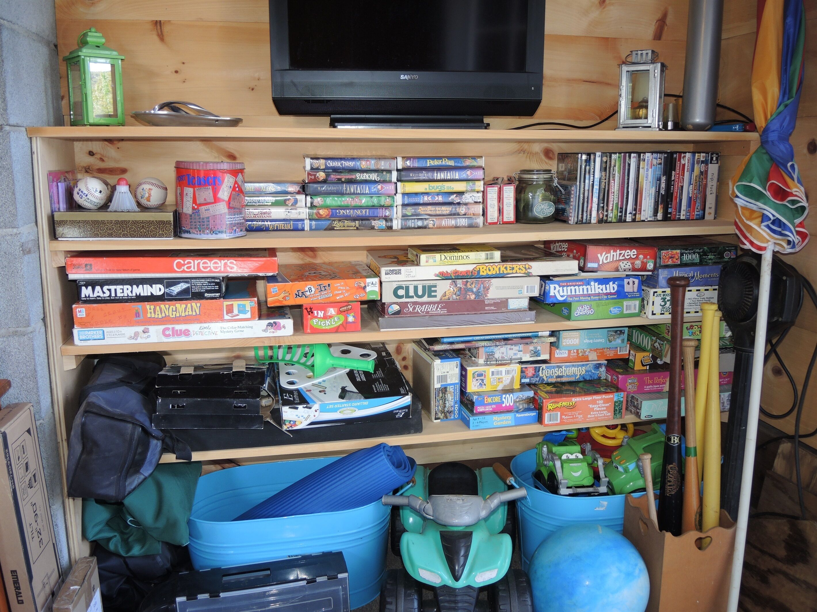 A shelf with various board games, a television, and some storage bins.