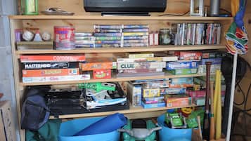 A shelf with various board games, a television, and some storage bins.