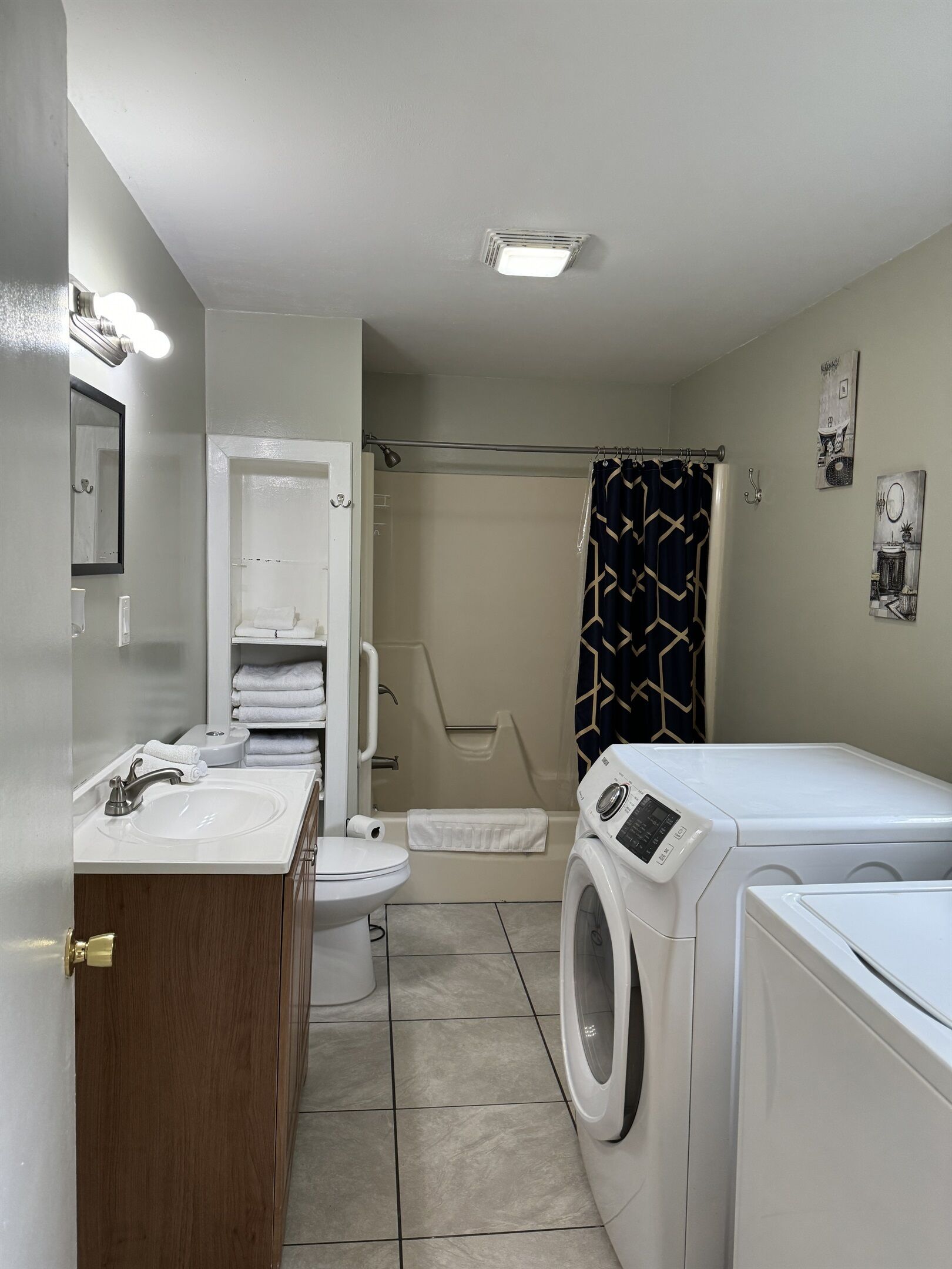 Une petite salle de bain comprenant un lavabo, des toilettes, une douche et un lave-linge.