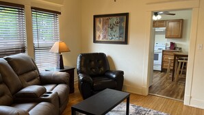 A living room with a leather sofa, a black leather chair, a coffee table, and a painting on the wall. - City Fox 1, 1 of 4, recent renovation in Oneonta, Convenient to All Star Village (Oneonta)