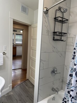 A bathroom with a shower, a towel rack, and a sink.