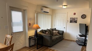 Un salon avec un canapé, une lampe, un téléviseur et une porte.