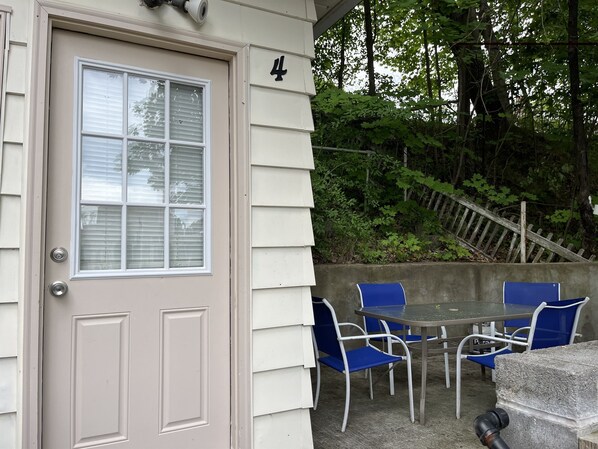 A beige door with a window, number 4, and a patio area with a table and blue chairs. - City Fox 4, #4 of 4 - new renovation in Oneonta, convenient to All Star Village (Oneonta)
