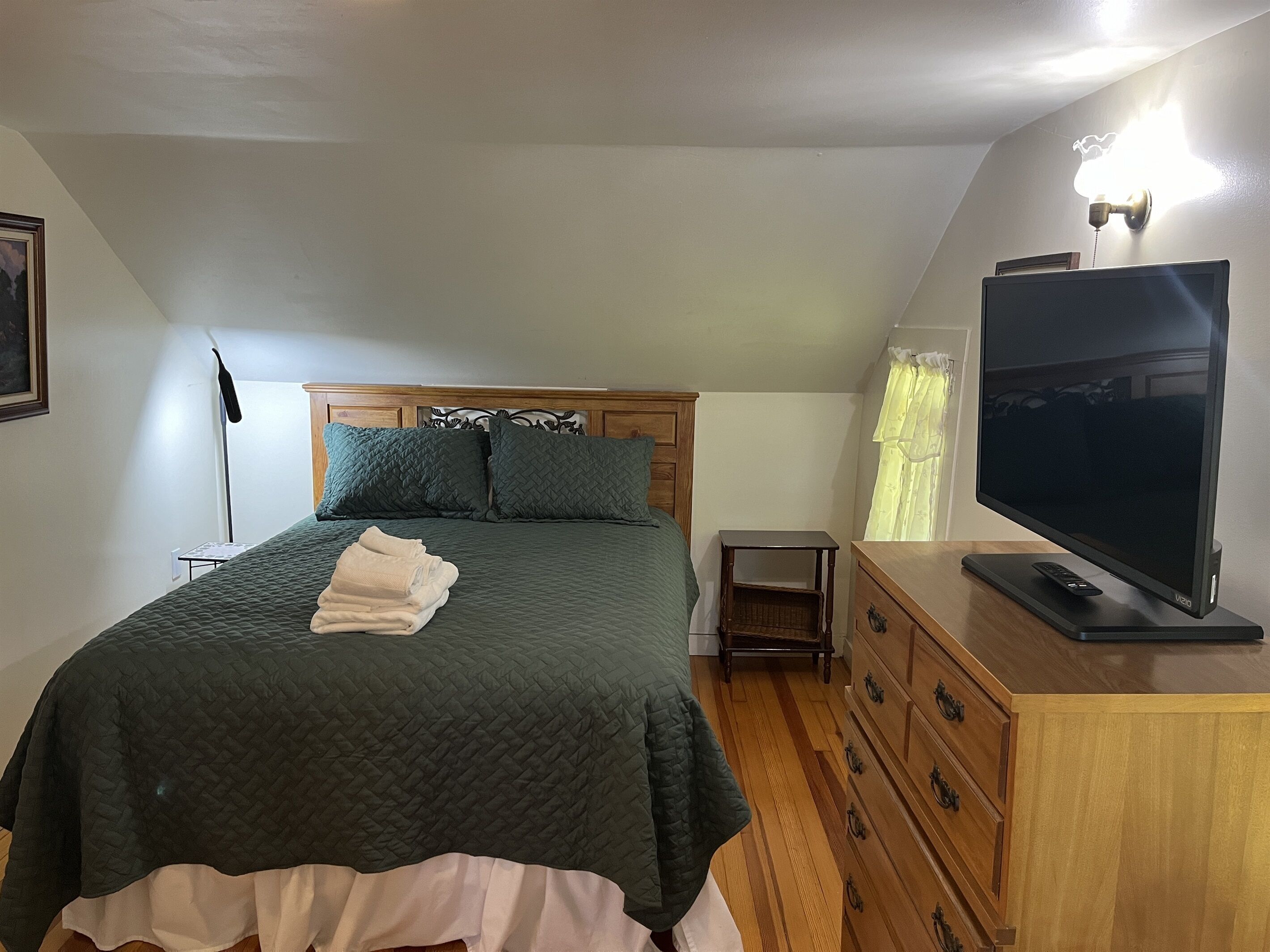A bedroom with a bed, a dresser, a television, and a nightstand.