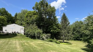 Ein grünes Rasenstück mit einem weißen Gebäude, Bäumen und blauem Himmel.