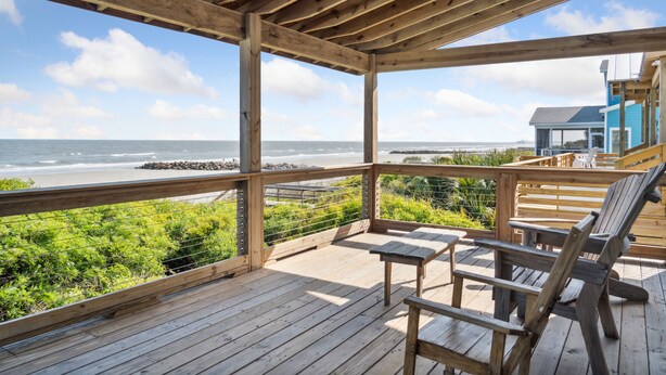 Un muelle de madera con vista al océano, una torre de salvavidas y un pabellón.