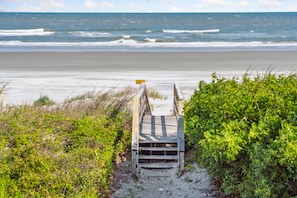 Eine Holztreppe führt zu einem Strand mit Blick auf den Ozean.