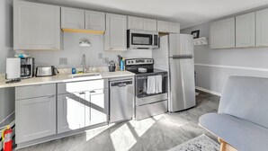 A modern kitchen with grey cabinets, a stainless steel refrigerator, a microwave, a dishwasher, and a stove. - #1 of 11 Units in Village of Cooperstown Apt Bldg (Cooperstown)