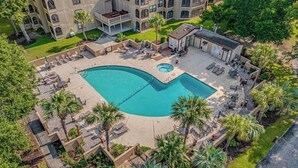 Vue aérienne d’un hôtel doté d’une grande piscine, d’espaces de détente en plein air et d’un aménagement paysager luxuriant.