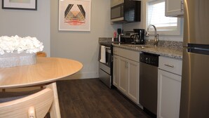 A modern kitchen with stainless steel appliances, a granite countertop, and a dining area with a wooden table and chairs.