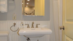 A bathroom with a white sink, a mirror, a toilet, and a shower curtain.