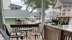 A wooden deck with outdoor seating, including chairs and a table.