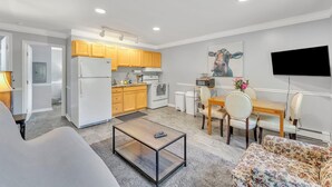 Una cocina moderna con electrodomésticos blancos, armarios de madera y un comedor con mesa y sillas.