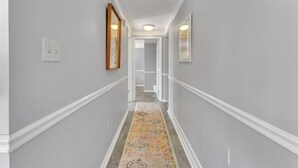 Un pasillo con paredes gris claro, molduras blancas y una alfombra colorida.
