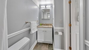 A narrow bathroom with a toilet, sink, and mirror.