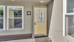 A house with a yellow door, two windows, and a small porch area.