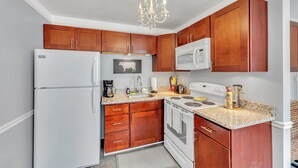 A kitchen with wooden cabinets, a white refrigerator, a microwave, a stove, and a chandelier.