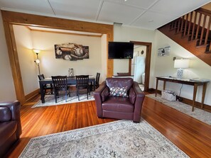 A living room with a dining area, a leather sofa, a TV, and a staircase. - Diamond Dreams, Very close to Dreams Park, Recent update, fire pit, large yard (Cooperstown)