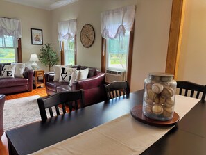 A living room with a dark wooden table, leather sofas, a clock, and a window with curtains.