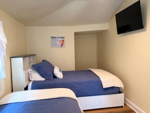 A bedroom with two beds, a white wardrobe, a flat-screen TV mounted on the wall, and a poster on the wall. - Diamond Dreams, Very close to Dreams Park, Recent update, fire pit, large yard (Cooperstown)