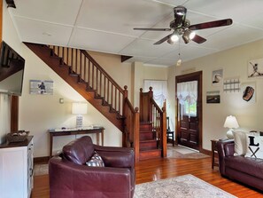 A living room with a wooden staircase, a ceiling fan, and a door labeled 'Coppershawn.' - Diamond Dreams, Very close to Dreams Park, Recent update, fire pit, large yard (Cooperstown)