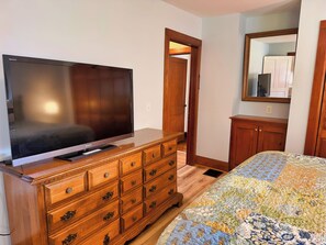A bedroom with a large flat-screen TV on a wooden dresser, a bed with a patterned quilt, and a wooden wardrobe. - Diamond Dreams, Very close to Dreams Park, Recent update, fire pit, large yard (Cooperstown)