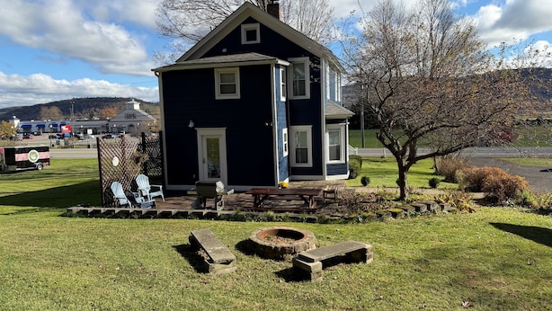 Una casa a due piani con un portico, un piccolo giardino e un vialetto.